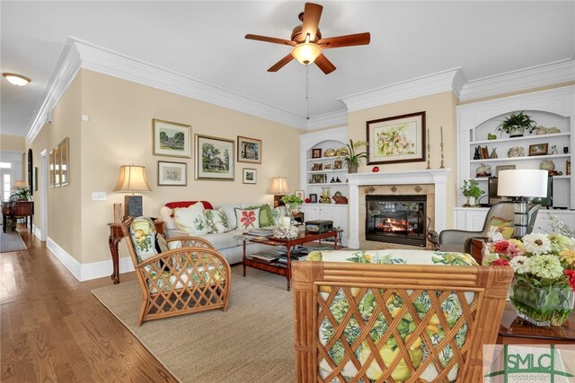 102 Reserve Cir, Savannah, GA 31421 - living area with ornamental molding, built in shelves, a ceiling fan, wood finished floors, and a fireplace