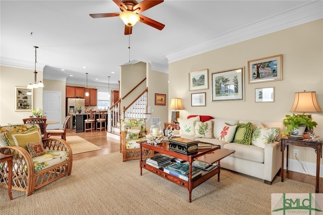 living room with ceiling fan, ornamental molding, and light wood-type flooring