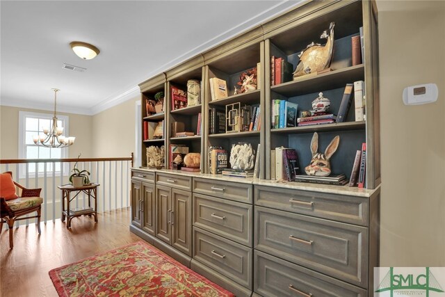 living area with crown molding, a chandelier, and light hardwood / wood-style floors