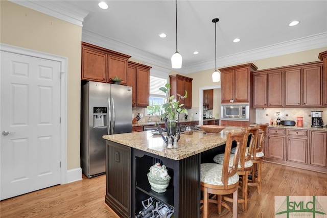 kitchen with light stone countertops, light hardwood / wood-style flooring, appliances with stainless steel finishes, a kitchen island, and ornamental molding