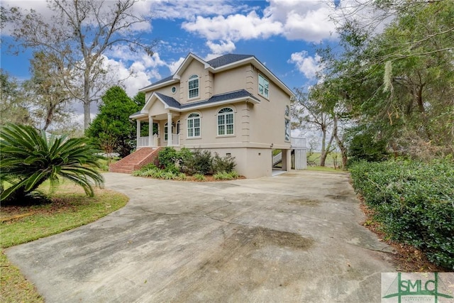 view of front of house featuring a porch, stairway, driveway, and stucco siding