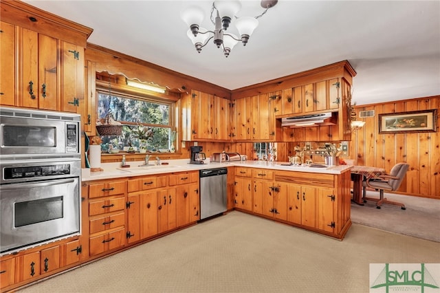 kitchen featuring sink, a notable chandelier, wood walls, light colored carpet, and appliances with stainless steel finishes