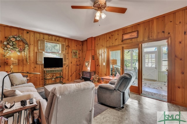 living room featuring ceiling fan, wooden walls, and ornamental molding