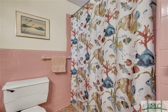 bathroom with tile patterned floors, toilet, tile walls, and curtained shower