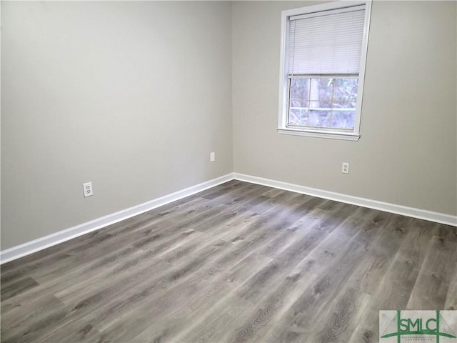 spare room featuring dark wood-type flooring and baseboards