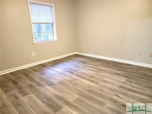 spare room featuring baseboards and wood finished floors