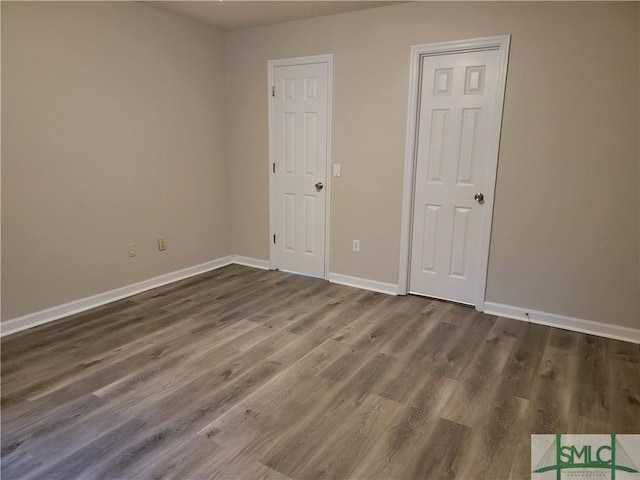 unfurnished room featuring dark wood-style flooring and baseboards