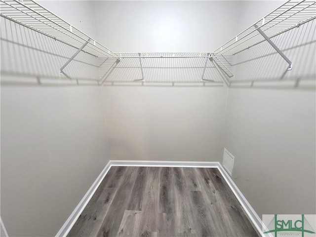 walk in closet with dark wood finished floors and visible vents