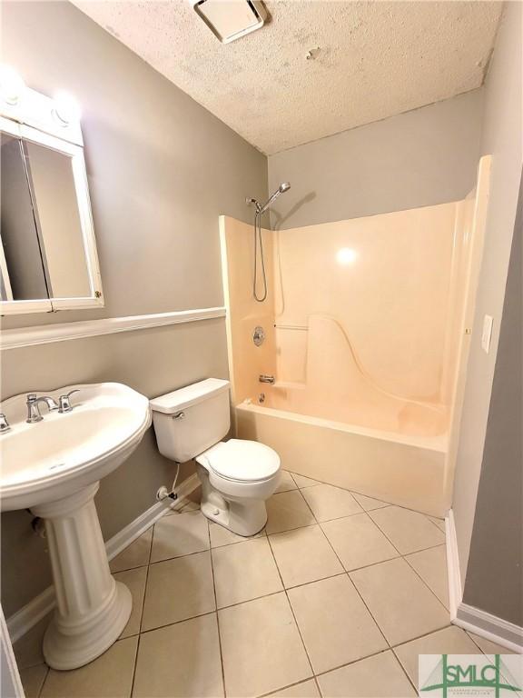 bathroom featuring shower / bath combination, toilet, a textured ceiling, tile patterned flooring, and baseboards