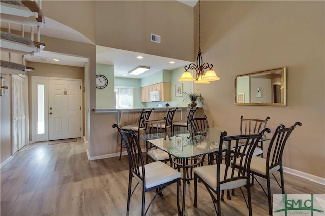 dining room featuring light hardwood / wood-style flooring, a chandelier, and a high ceiling