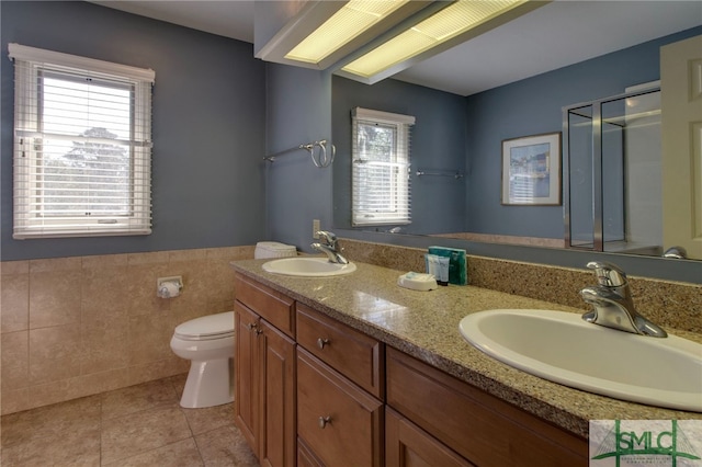 bathroom with tile patterned flooring, vanity, toilet, and tile walls