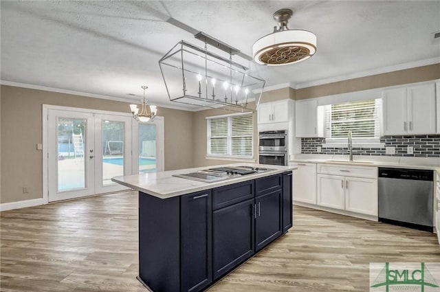 kitchen with stainless steel appliances, sink, pendant lighting, and white cabinets