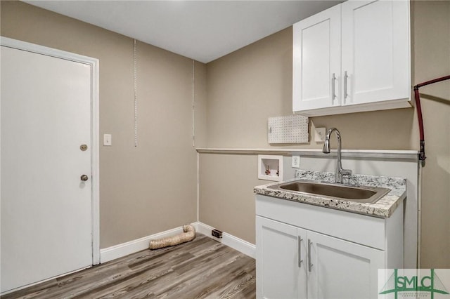 laundry room with cabinets, hookup for a washing machine, sink, and light hardwood / wood-style flooring