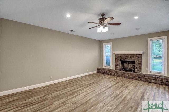 unfurnished living room with a brick fireplace, hardwood / wood-style floors, and ceiling fan