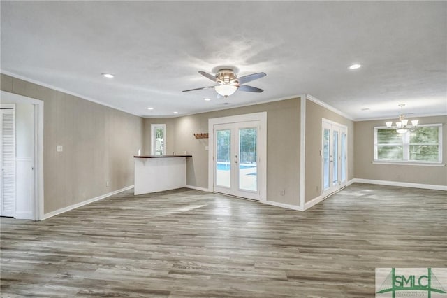 unfurnished living room with french doors, a healthy amount of sunlight, ornamental molding, and hardwood / wood-style floors