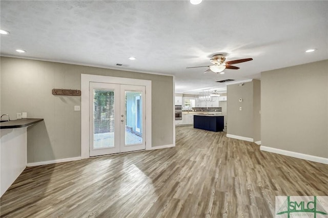 unfurnished living room with wood-type flooring, ceiling fan, and french doors