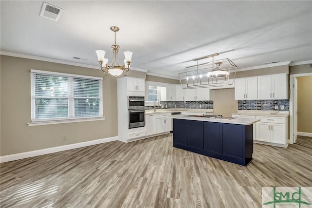 kitchen featuring a kitchen island, white cabinetry, sink, hanging light fixtures, and an inviting chandelier