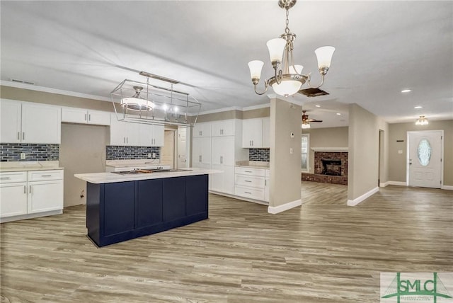 kitchen with hanging light fixtures, a center island with sink, gas cooktop, light hardwood / wood-style floors, and white cabinets