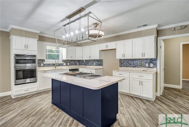 kitchen with stainless steel appliances, a kitchen island, sink, and white cabinets