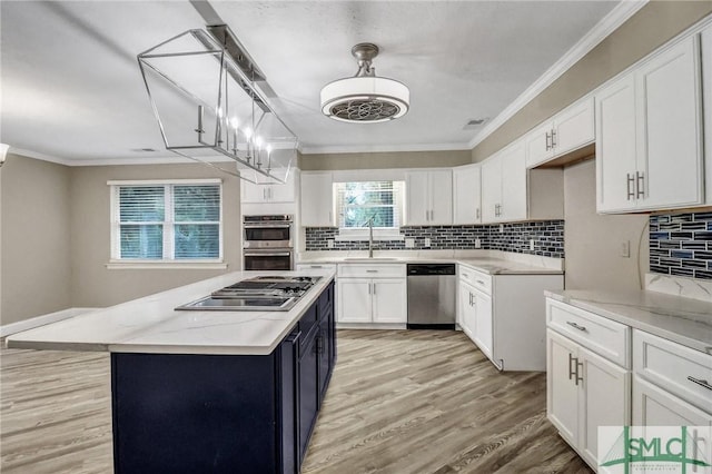 kitchen featuring sink, appliances with stainless steel finishes, ornamental molding, white cabinets, and a kitchen island