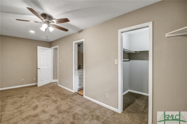 unfurnished bedroom featuring connected bathroom, carpet flooring, a spacious closet, ceiling fan, and a closet