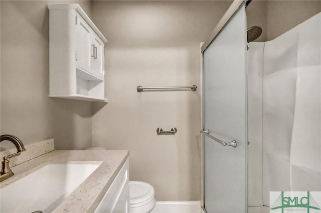 bathroom featuring a shower with door, vanity, and toilet