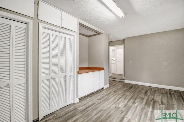 unfurnished bedroom with multiple closets, a textured ceiling, and light wood-type flooring