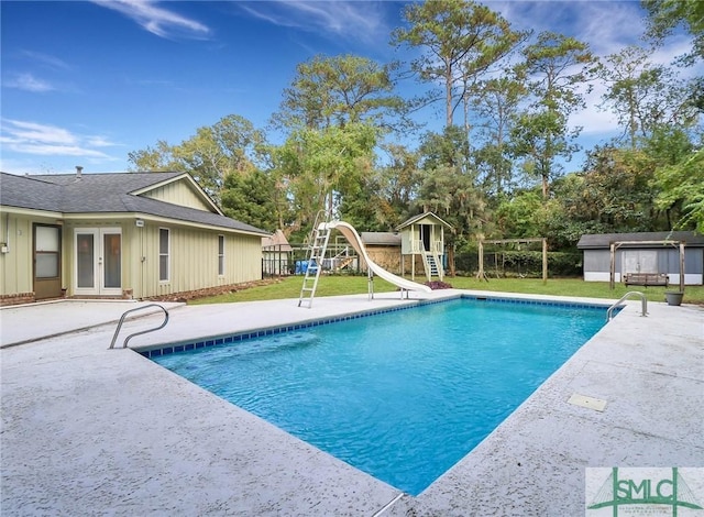 view of swimming pool with french doors, a water slide, a shed, a playground, and a patio