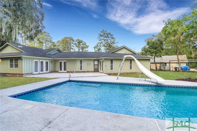 view of swimming pool with a water slide, a lawn, a patio area, and french doors