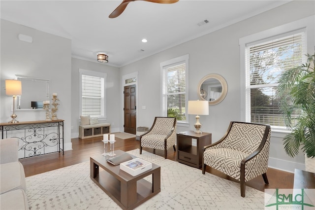 living area featuring wood-type flooring, plenty of natural light, and crown molding