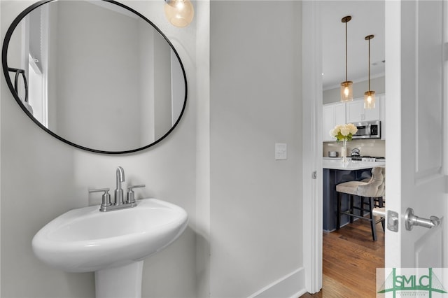 bathroom with hardwood / wood-style flooring, crown molding, sink, and tasteful backsplash