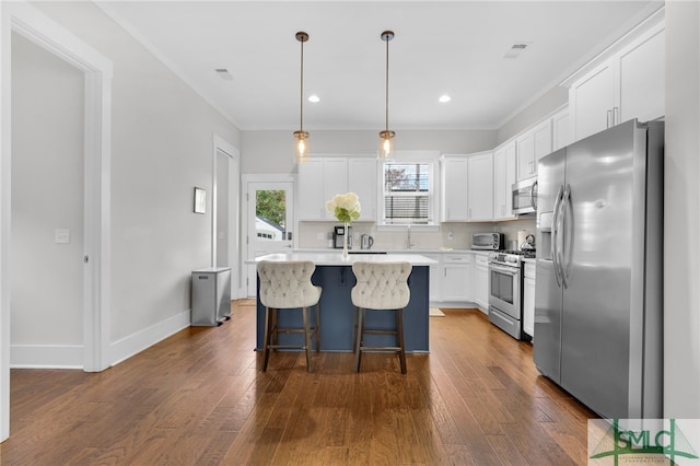 kitchen featuring white cabinetry, stainless steel appliances, dark hardwood / wood-style flooring, pendant lighting, and a kitchen island