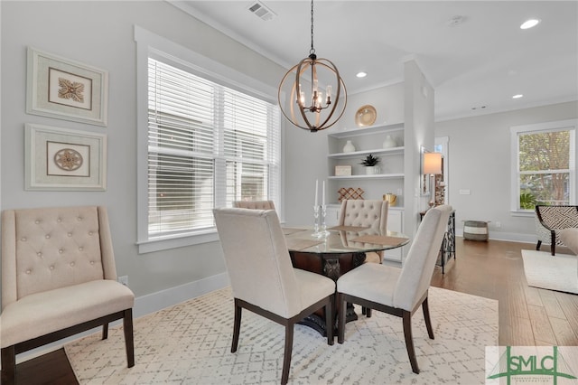 dining area featuring an inviting chandelier, light hardwood / wood-style flooring, and crown molding