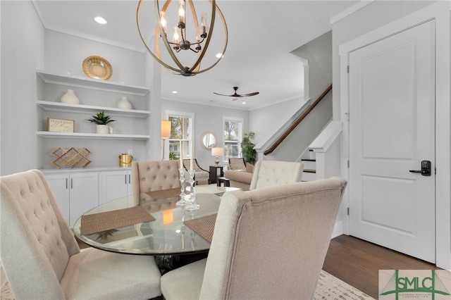 dining space with ornamental molding, ceiling fan with notable chandelier, and hardwood / wood-style flooring