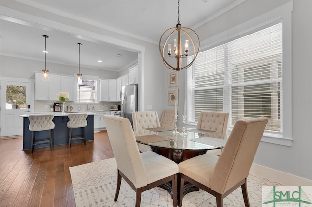 dining area with a chandelier, ornamental molding, dark wood-type flooring, and sink