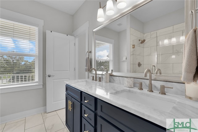 bathroom with plenty of natural light, tiled shower, and vanity