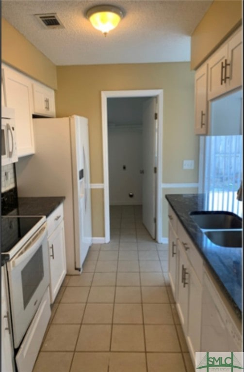 kitchen with white cabinets, light tile patterned floors, and white appliances