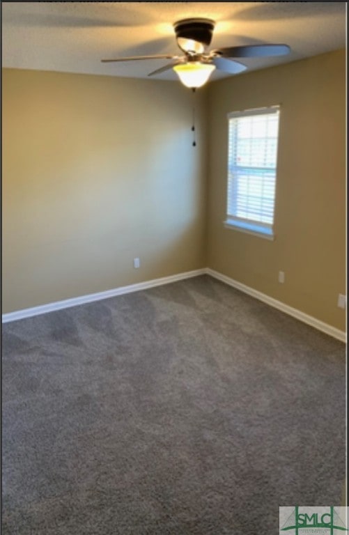 spare room featuring dark colored carpet and ceiling fan