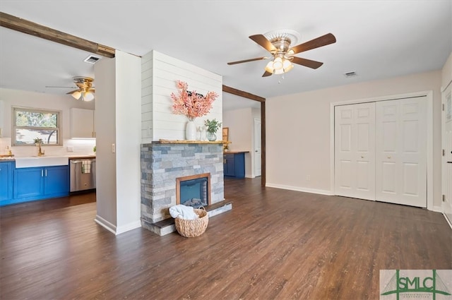 unfurnished living room with a fireplace, ceiling fan, sink, and dark wood-type flooring