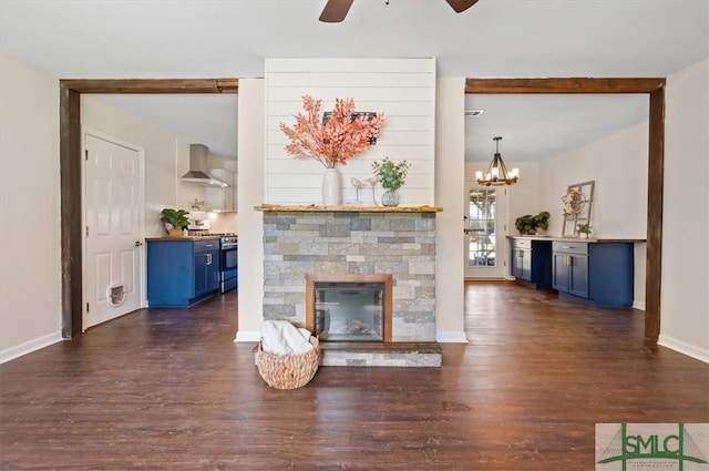 unfurnished living room featuring dark hardwood / wood-style floors, a stone fireplace, and ceiling fan with notable chandelier