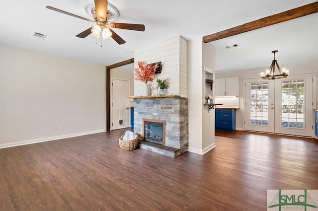 unfurnished living room featuring beam ceiling, french doors, dark hardwood / wood-style floors, a fireplace, and ceiling fan with notable chandelier