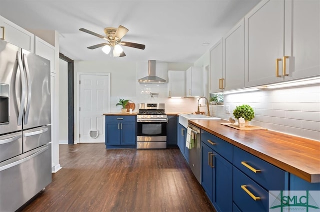 kitchen with white cabinets, wall chimney range hood, sink, butcher block counters, and stainless steel appliances