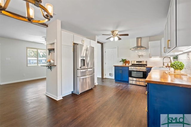 kitchen with white cabinetry, sink, stainless steel appliances, wall chimney range hood, and blue cabinets