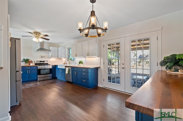 kitchen featuring blue cabinetry, french doors, stainless steel appliances, wall chimney range hood, and white cabinets