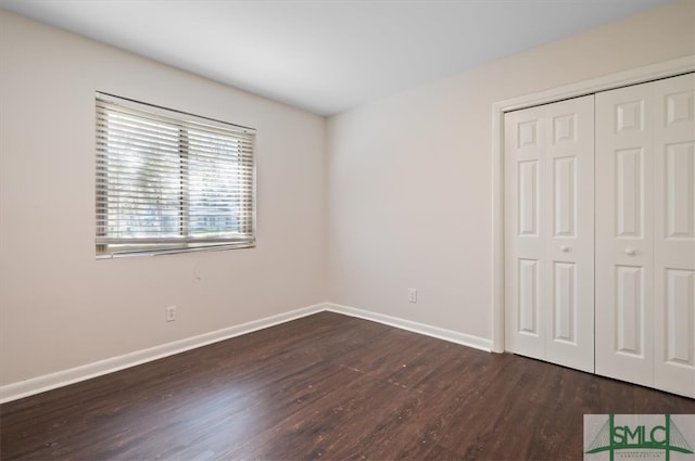 unfurnished bedroom with dark hardwood / wood-style flooring and a closet