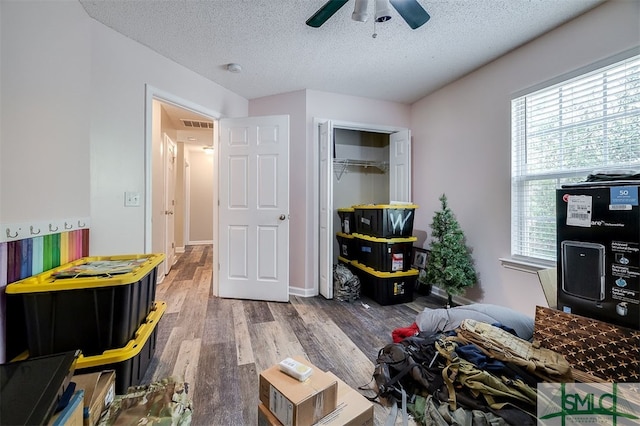 bedroom featuring a closet, multiple windows, ceiling fan, and hardwood / wood-style floors