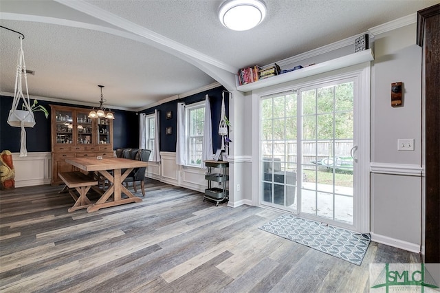 dining room with hardwood / wood-style floors, a textured ceiling, crown molding, and a healthy amount of sunlight