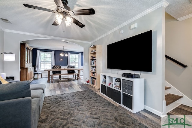 living room featuring hardwood / wood-style floors, ceiling fan with notable chandelier, a textured ceiling, and ornamental molding