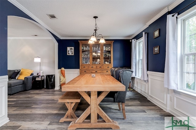 dining space featuring crown molding, dark hardwood / wood-style flooring, and a notable chandelier