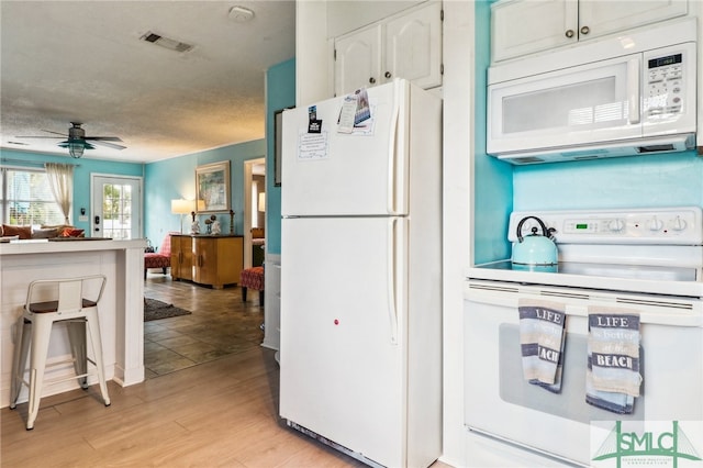 kitchen with a textured ceiling, white appliances, ceiling fan, white cabinets, and light hardwood / wood-style floors